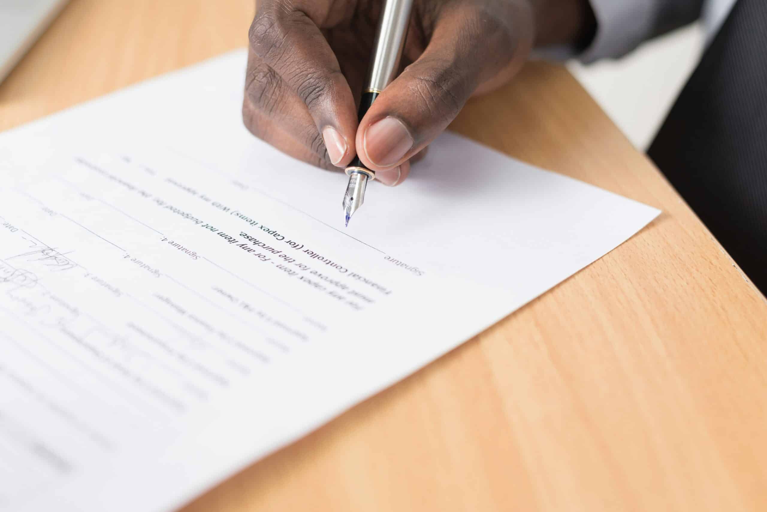A hand signing a contract.
