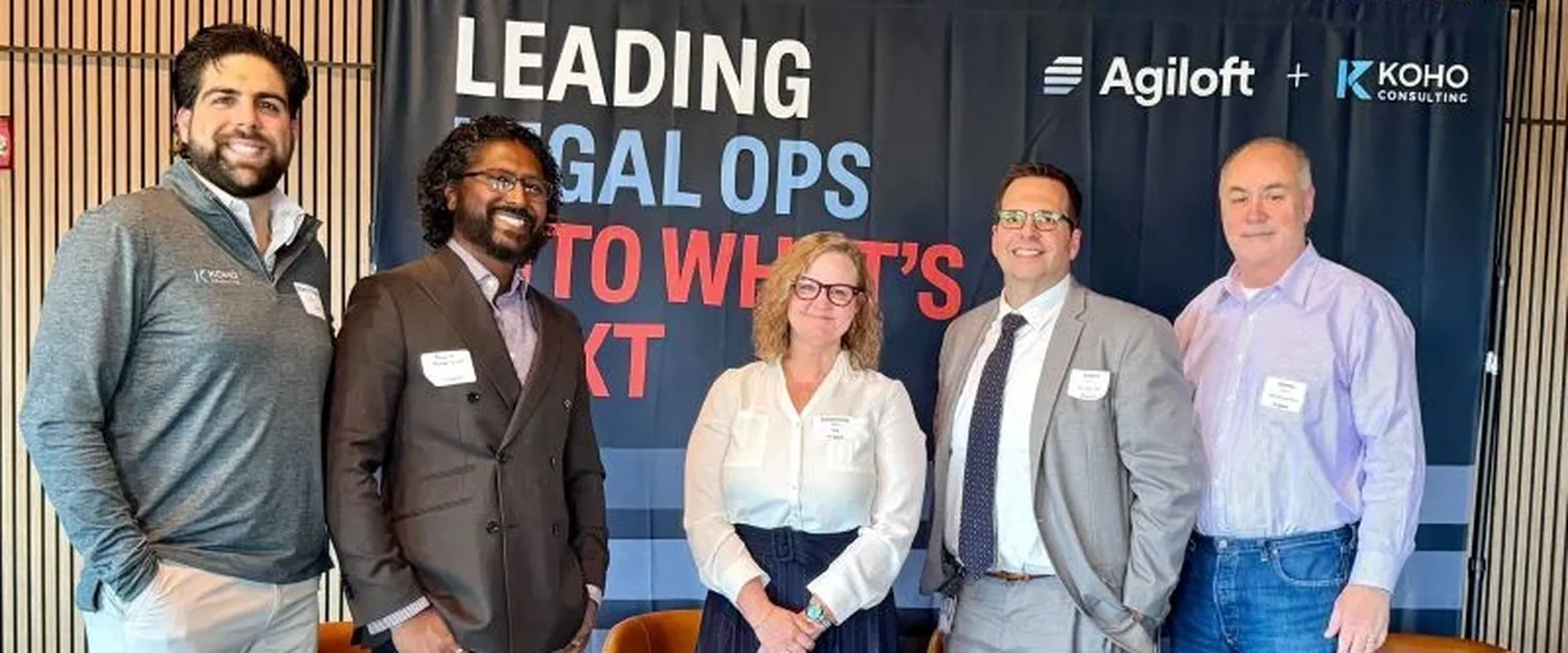 The Koho and Agiloft teams together at a Leading Legal Ops event, in front of the Agiloft and Koho co-branded backdrop.