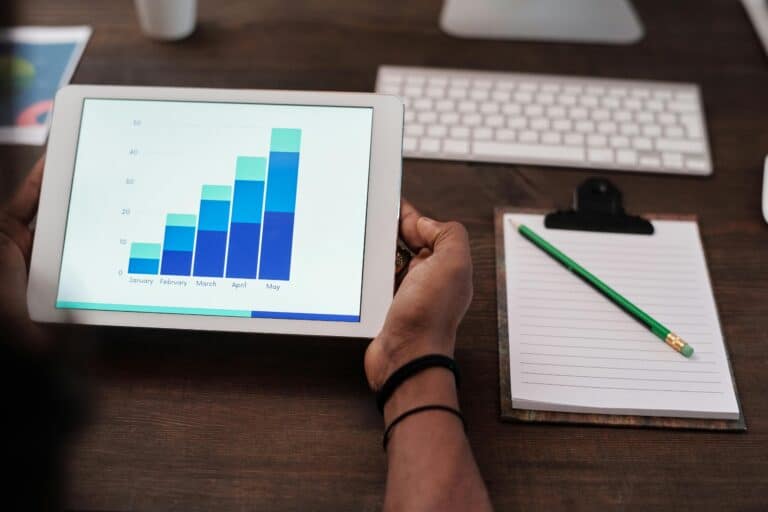 CLM-empowered contract analysis with bar graphs on a tablet screen and a pencil and paper nearby.